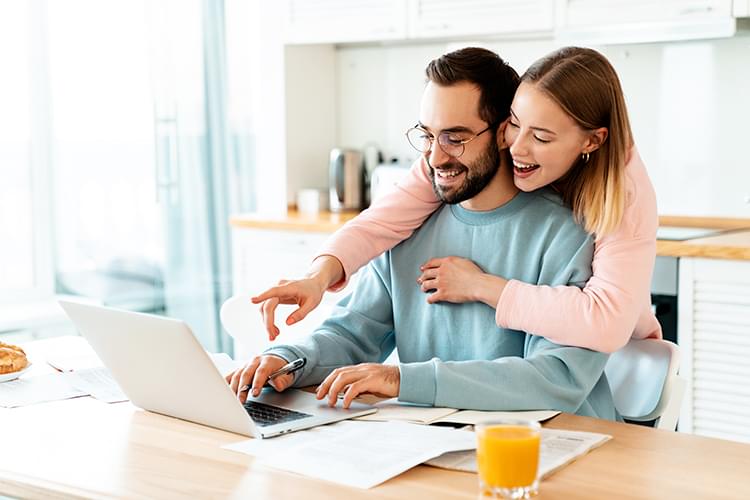 Smiling woman taking notes in front of laptop